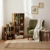 A cozy living room corner with wooden crates used as shelving, a green armchair, and a small side table. Produktbild-Vorschau