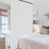 A bedroom scene divided by a curtain, showing two beds and a window. Náhled obrázku produktu