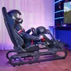 A person wearing a racing helmet and suit is sitting in a racing simulator cockpit, playing a racing game on a large screen. Produktbild-Vorschau