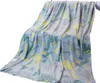 A blanket with a dinosaur pattern is draped over a surface. Náhled obrázku produktu