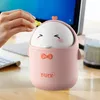 A hand is shown dropping an item into a cute, pink duck-shaped trash can on a desk. Produktbild-Vorschau