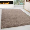A beige shaggy rug in a modern living room setting with a fireplace and large windows.