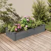 A raised garden bed filled with pink and green plants sits on a wooden deck next to a wall. Produktbild-Vorschau