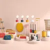 A collection of bathroom accessories and decor items arranged on display stands against a light pink background. Podgląd zdjęcia produktu