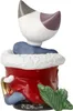 A close-up view of a ceramic figurine of a cat sitting in a red sack with white trim. Anteprima dell’immagine prodotto