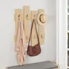 A wooden coat rack with a robe, handbag, and hat hanging on it, placed above a bench in an entryway. Náhled obrázku produktu