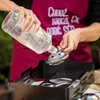 A person is pouring liquid from a bottle into a metal device. Produktbild-Vorschau