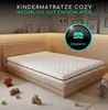 A child's mattress on a wooden bed frame in a nursery setting, with wooden toys scattered around. Produktbild-Vorschau