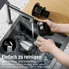 Hands cleaning a vacuum cleaner part under a faucet in a sink. Produktbild-Vorschau