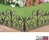 A decorative metal fence in front of a garden with flowers. Produktbild-Vorschau