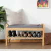 A shoe bench with a cushion, a pillow, and shoes on the shelves. Produktbild-Vorschau