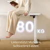 A person is sitting on a white desk, reading a book. Large glowing numbers '80' and 'KG' are superimposed on the wall behind the desk, along with German text. Produktbild-Vorschau