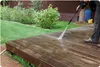 A person is pressure washing a wooden deck in a backyard setting. Náhľad obrázku produktu