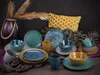 A collection of ceramic tableware, including plates and bowls, arranged on a dark surface with decorative elements. Náhľad obrázku produktu
