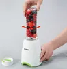 A hand is shown securing a blender cup filled with berries onto the blender base. Podgląd zdjęcia produktu