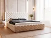 A tufted beige upholstered bed with a headboard and frame, set in a bedroom with soft lighting and sheer curtains.