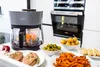 A kitchen scene featuring an air fryer and various food items prepared for cooking. Produktbild-Vorschau