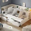 A white modular bed frame with multiple storage compartments and drawers, set up in a corner of a room with blue walls and a wooden floor. Náhľad obrázku produktu