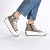 A pair of women's high-top sneakers with a leopard print pattern, worn by a person. Produktbild-Vorschau