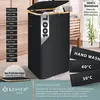 A black laundry basket with a wooden rim and lid, shown in a room setting with wooden furniture in the background. Various labels and text overlays highlight product features and washing instructions. Produktbild-Vorschau