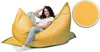 A woman is sitting on a large yellow beanbag chair. Produktbild-Vorschau