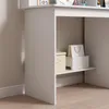 A close-up view of the lower section of a white desk, showing a small shelf with storage boxes. Podgląd zdjęcia produktu