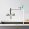 A kitchen faucet mounted on a wall above a sink, with water flowing from it. Podgląd zdjęcia produktu