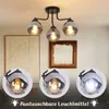 A collage showing a black ceiling lamp with three glass shades, and close-ups of the shades with different light bulbs. Produktbild-Vorschau
