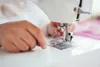 A close-up shot of hands using a sewing machine. Produktbild-Vorschau