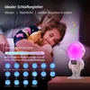 A mother and child sleeping in bed, with a night light/speaker in the foreground. Produktbild-Vorschau
