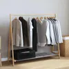 A wooden clothes rack with various garments hanging on it, placed against a light gray wall. Anteprima dell’immagine prodotto