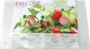 A clear plastic cutting board with a salad on it, presented in its packaging. Produktbild-Vorschau