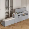 A grey storage bench with a beige upholstered seat is placed in front of a white wardrobe with glass doors. Produktbild-Vorschau