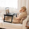 A woman is relaxing on a couch with a laptop on a portable desk in front of her. Podgląd zdjęcia produktu