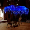 An outdoor patio at night, decorated with blue icicle lights draped over an umbrella. Produktbild-Vorschau