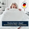 A woman peeking out from under a white duvet in a bedroom. Produktbild-Vorschau