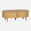 A light brown, oval-shaped coffee table with fluted sides and two doors, shown from the front on a plain background. Produktbild-Vorschau