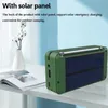 A green radio with a solar panel on the back is placed on a white table next to an open book and a vase with cotton stems. Produktbild-Vorschau