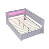 A light gray upholstered bed frame with a slatted mattress support and integrated LED lighting in the headboard emitting a pink glow. Náhled obrázku produktu