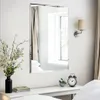 A mirror is mounted on a wall above a white console table, reflecting a window and curtains. Decorative items like a vase with flowers, books, a small plant, and an alarm clock are placed on the table. Produktbild-Vorschau