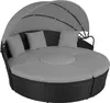 A round, rattan daybed with a canopy and cushions, set against a white background. Voir les images du produit
