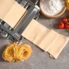 A pasta machine is shown with sheets of dough being processed, alongside fresh pasta nests, flour, and cherry tomatoes. Náhľad obrázku produktu