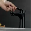 A hand is shown turning on a black faucet in a bathroom. Náhľad obrázku produktu