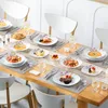 A beautifully set dining table with multiple place settings, each featuring a plate with food and cutlery. Produktbild-Vorschau