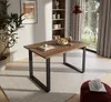 A dining table in a well-lit room with a large window overlooking a garden. Produktbild-Vorschau
