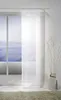 A sheer white panel curtain is shown hanging in front of a large window with a view of the ocean. Podgląd zdjęcia produktu