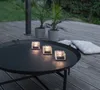 Three LED candles on a black coffee table on a wooden deck. Podgląd zdjęcia produktu