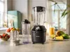 A blender set with accessories, fruit, and a glass of juice on a kitchen counter. Anteprima dell’immagine prodotto