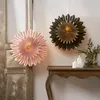 Two decorative paper stars hang on a wall above a wooden console table with candles and greenery. Podgląd zdjęcia produktu