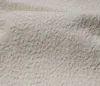 A close-up view of a textured, light-colored fabric, likely a bed frame or upholstery. Produktbild-Vorschau